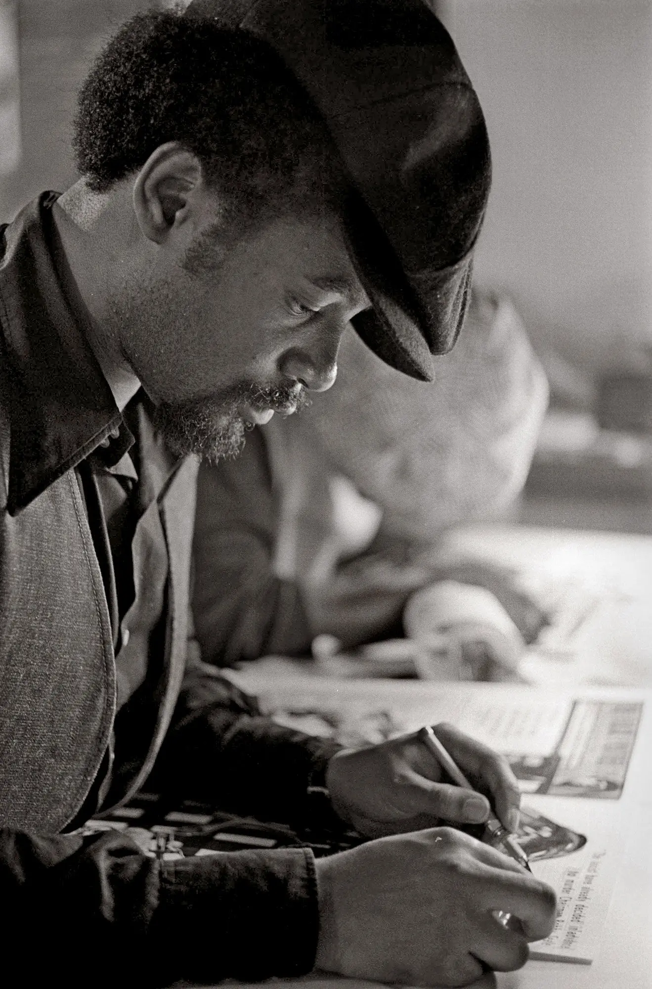 Black and white photos of Emory Douglas at work on The Black Panther newspaper.